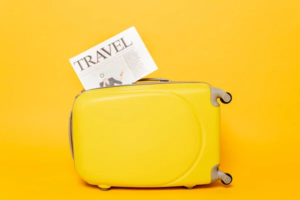 Travel newspaper on colorful suitcase on yellow background — Stock Photo