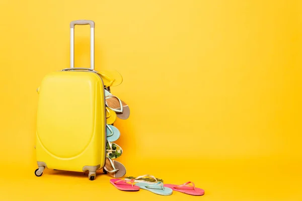 Sac de voyage avec des tongs colorées sur fond jaune — Photo de stock