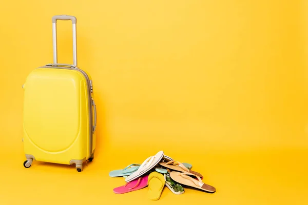 Bolsa de viaje con chanclas de colores sobre fondo amarillo - foto de stock