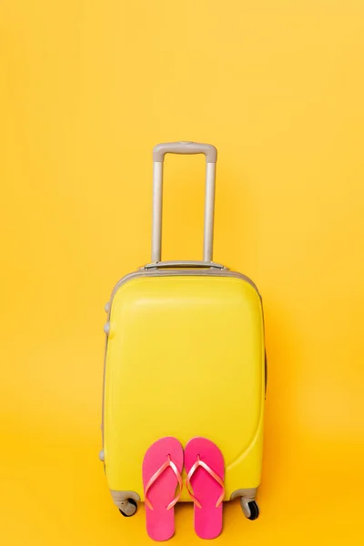 Bolsa de viaje con chanclas rosadas aisladas sobre fondo amarillo - foto de stock
