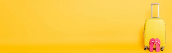 Sac de voyage avec tongs roses sur fond jaune, panoramique — Photo de stock