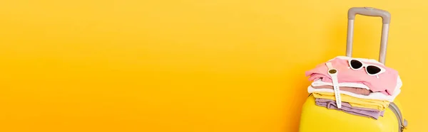Sac de voyage avec vêtements d'été et accessoires isolés sur jaune, vue panoramique — Photo de stock