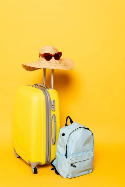 Туристична сумка з сонячним капелюхом та сонцезахисними окулярами біля рюкзака на жовтому фоні — стокове фото