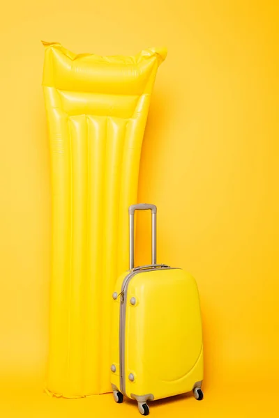 Borsa da viaggio vicino piscina galleggiante su sfondo giallo — Foto stock