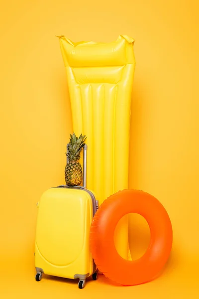 Дорожня сумка з ананасом біля басейну плаває на жовтому фоні — стокове фото