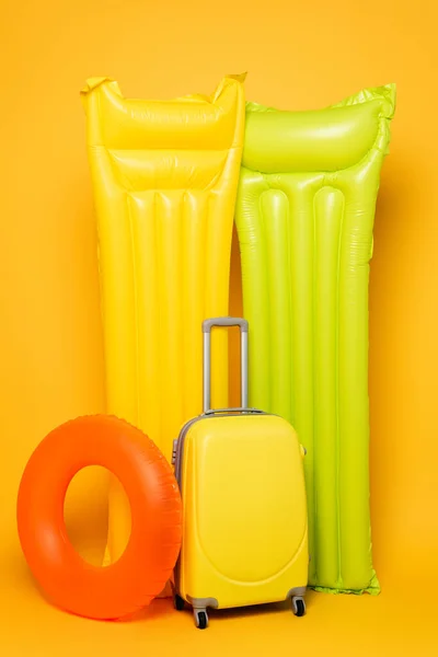 Sac de voyage avec flotteurs de piscine sur fond jaune — Photo de stock