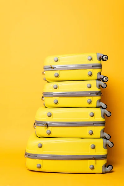 Pila de bolsas de viaje sobre fondo amarillo - foto de stock