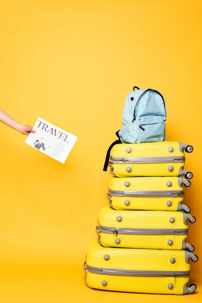 Vue recadrée d'une femme tenant un journal de voyage près d'un sac à dos bleu sur des sacs de voyage jaune — Photo de stock