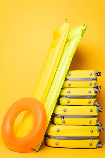 Sacos de viagem com flutuadores de piscina no fundo amarelo — Fotografia de Stock