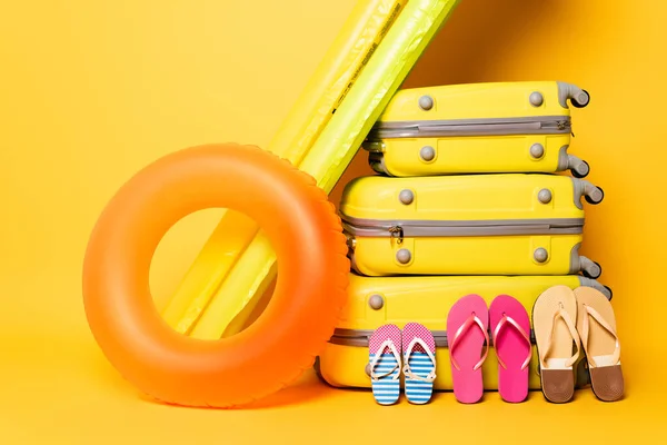 Bolsas de viaje con chanclas familiares y flotadores de piscina en amarillo - foto de stock