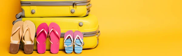 Travel bags with family flip flops isolated on yellow, panoramic shot — Stock Photo
