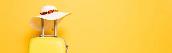 Saco de viagem amarelo com chapéu de sol e óculos de sol isolados em amarelo, tiro panorâmico — Fotografia de Stock