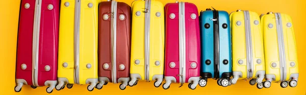 Coloridas bolsas de viaje en pila aisladas en amarillo, plano panorámico - foto de stock