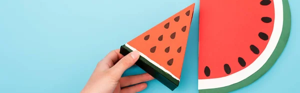 Partial view of female hand with paper watermelon slices on blue background, panoramic shot — Stock Photo