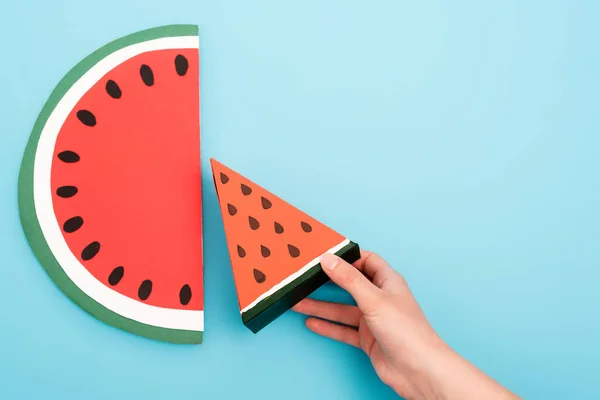 Teilansicht der weiblichen Hand mit Papier-Wassermelonenscheiben auf blauem Hintergrund — Stockfoto