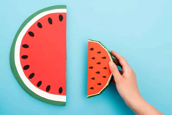 Teilansicht der weiblichen Hand mit Papier-Wassermelonenscheiben auf blauem Hintergrund — Stockfoto