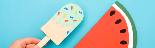 Cropped view of woman holding paper ice cream with sprinkles near watermelon on blue background, panoramic shot — Stock Photo