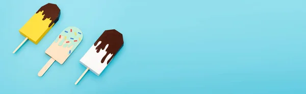 Draufsicht auf Papiereis mit Schokolade und Streusel auf blauem Hintergrund, Panoramaaufnahme — Stockfoto