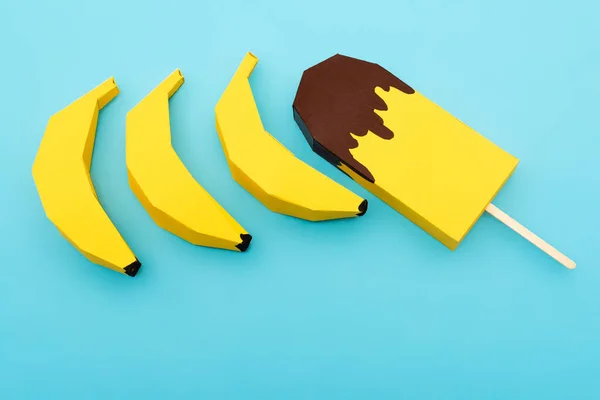 Вид зверху на паперові жовті банани та морозиво на синьому фоні — стокове фото