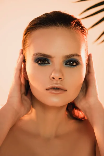 Selective focus of beautiful woman with makeup looking at camera on beige — Stock Photo