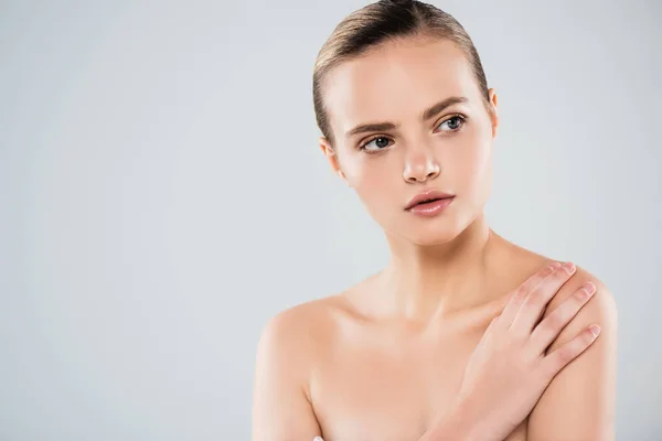 Nackte junge Frau schaut weg und berührt Schulter isoliert auf grau — Stockfoto