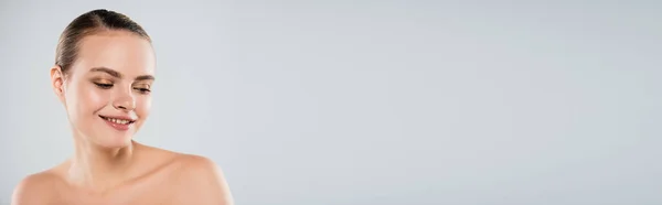 Panoramic concept of happy young woman smiling and looking away isolated on grey — Stock Photo