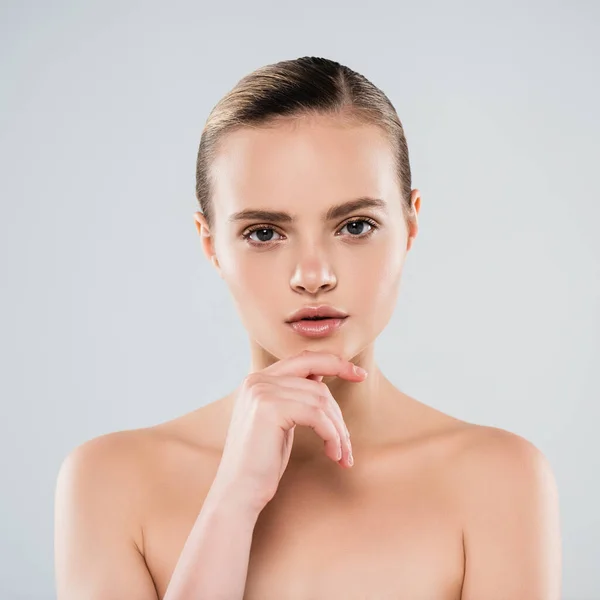 Naked young woman looking at camera and touching face isolated on grey — Stock Photo