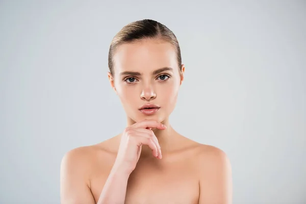 Mujer desnuda mirando a la cámara y tocando la cara aislada en gris - foto de stock