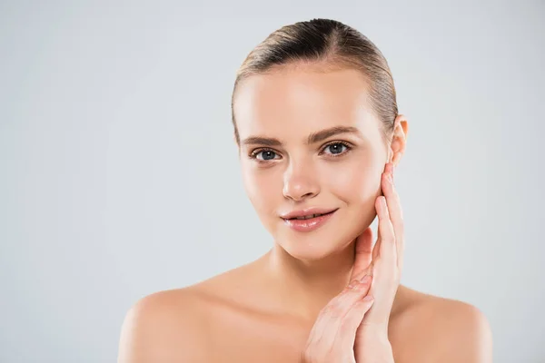 Glückliche und nackte Frau blickt in die Kamera, während sie Gesicht isoliert auf grau berührt — Stockfoto