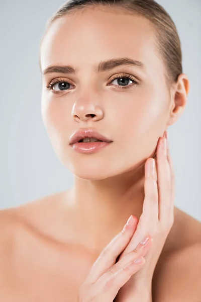 Attractive and naked woman looking at camera while touching face isolated on grey — Stock Photo