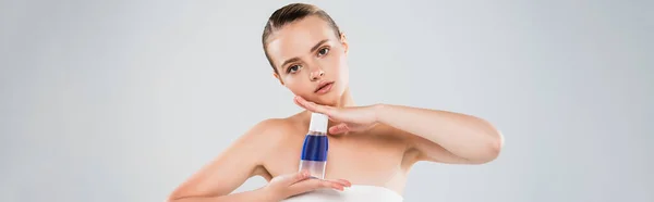 Panoramic crop of woman holding bottle with toner isolated on grey — Stock Photo