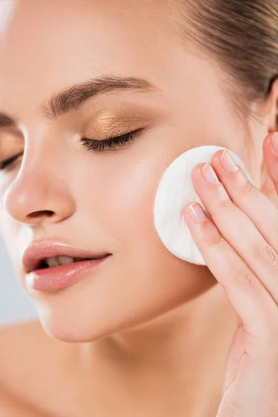 Close up of young woman holding cotton pad near face isolated on grey — Stock Photo