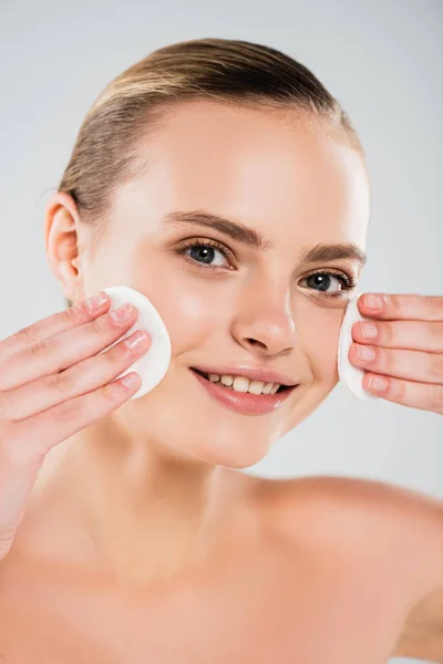 Happy young woman holding cotton pads near clean face isolated on grey — Stock Photo