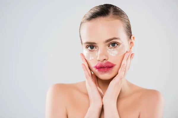 Nackte Frau mit Lippenmaske und Augenklappen, die sauberes Gesicht berühren, isoliert auf grau — Stockfoto