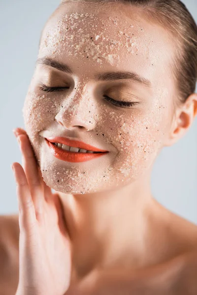 Close up de feliz jovem mulher aplicando scrub isolado no branco — Fotografia de Stock