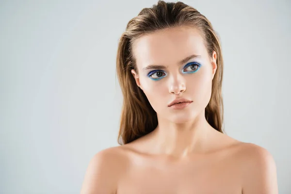 Jeune femme nue avec fard à paupières bleu regardant loin isolé sur blanc — Photo de stock