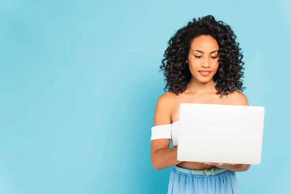 Encaracolado Africano americano mulher usando laptop em azul — Fotografia de Stock