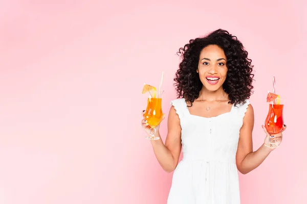 Joyeuse fille afro-américaine tenant des cocktails sur rose — Photo de stock