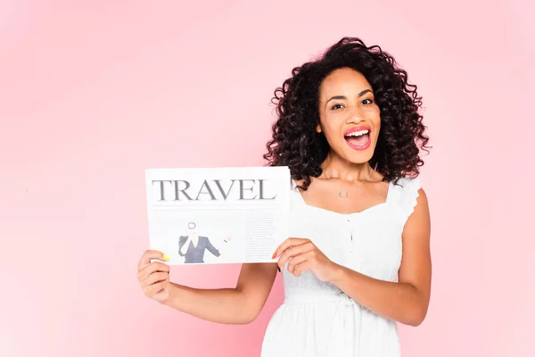 Animado menina afro-americana segurando jornal de viagem isolado em rosa — Fotografia de Stock