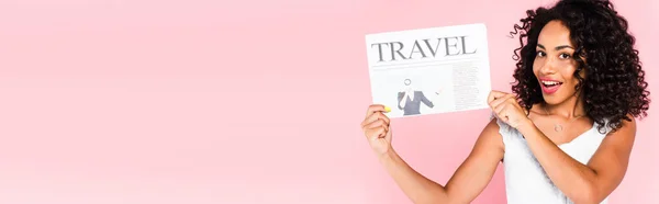 Website header of excited african american woman holding travel newspaper isolated on pink — Stock Photo