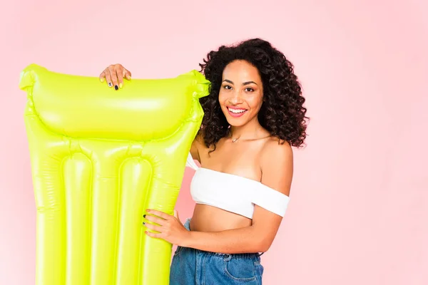 Happy african american girl standing near inflatable mattress isolated on pink — Stock Photo