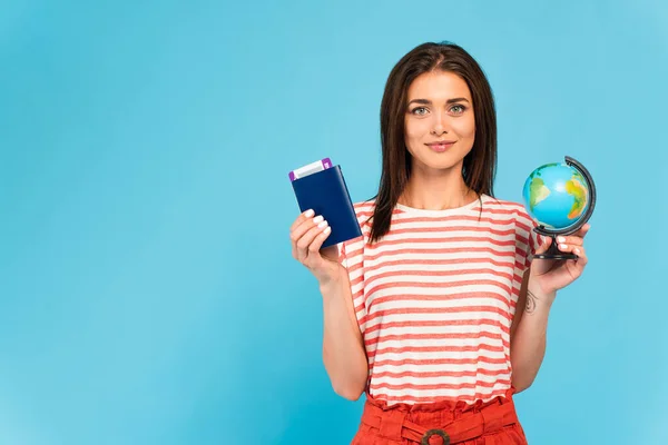 Chica atractiva sosteniendo pasaporte y globo aislado en azul - foto de stock