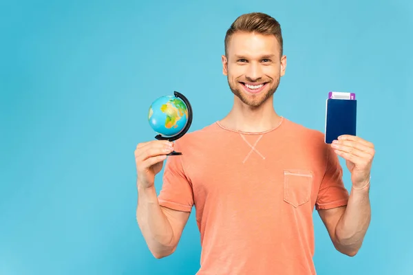 Homme heureux tenant passeport et globe isolé sur bleu — Photo de stock