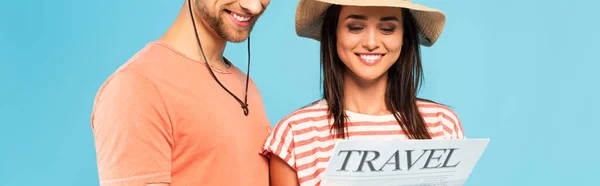 Horizontal crop of happy couple reading travel newspaper isolated on blue — Stock Photo