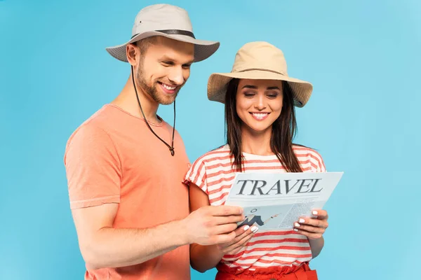 Feliz pareja leyendo periódico de viaje aislado en azul - foto de stock