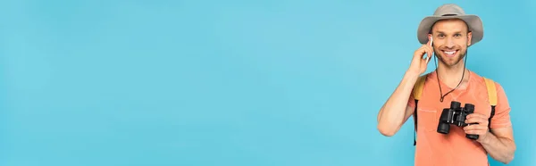 Заголовок сайта счастливый человек держит бинокль и говорить на смартфоне изолированы на синий — стоковое фото