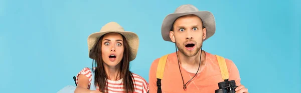 Panoramic crop of shocked couple in hats isolated on blue — Stock Photo