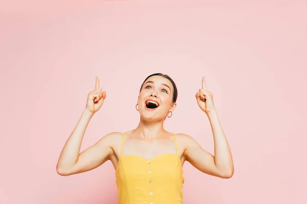 Excited brunette young woman pointing with fingers up isolated on pink — Stock Photo