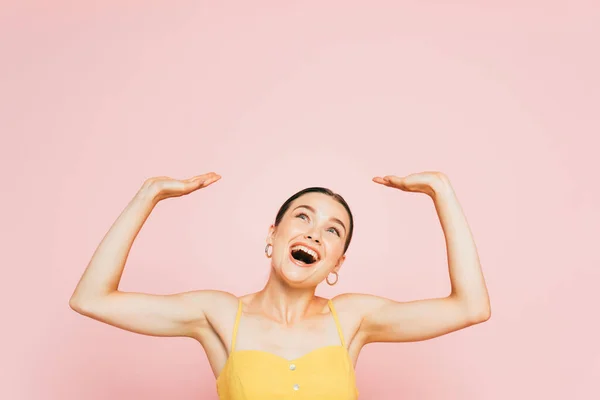 Excited brunette young woman with raised hands isolated on pink — Stock Photo