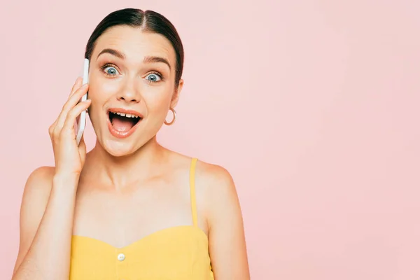 Excited brunette young woman talking on smartphone isolated on pink — Stock Photo